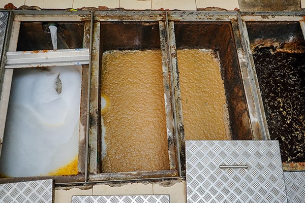 signs such as slow draining sinks and foul odors can indicate a need for grease trap maintenance